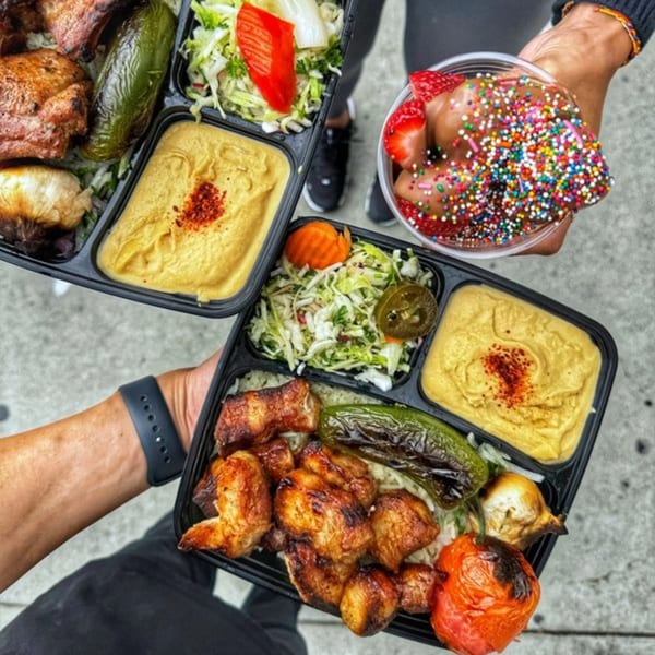 Two Ara's Shawarma plates with chicken, vegetables, hummus, and a dessert cup with sprinkles.