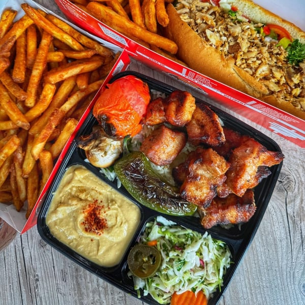 Ara's Shawarma chicken kebab plate with hummus, salad, grilled vegetables, fries, and a chicken shawarma sandwich.