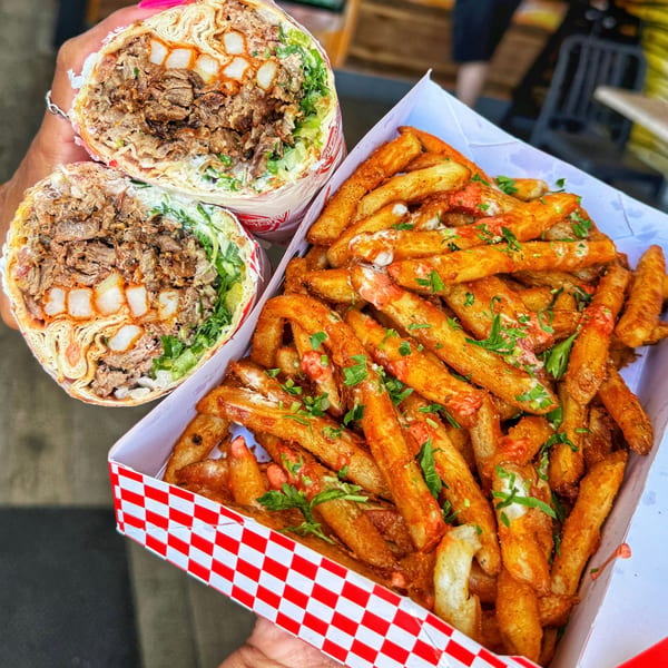 Two Ara's Shawarma wraps filled with meat and fries, next to a box of seasoned fries.